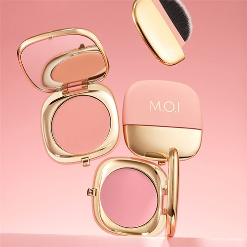 Image showing two M.O.I POWDER BLUSH compacts and arm swatches labeled No. 1 Cool Cool Girl Hồng Da and No. 2 Peachy Peach Babe Cam Đào. The compacts have gold lids, and the blushes are pink and peach-toned. Buy at MyAllures for a flawless finish!