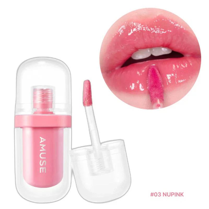 A bottle of AMUSE JEL-FIT TINT in pink, featuring a doe-foot applicator, sits open against a backdrop of a pink gloss smear. The word "AMUSE" is elegantly printed on the bottle. Purchase it at MyAllures for an effortless, glossy finish!