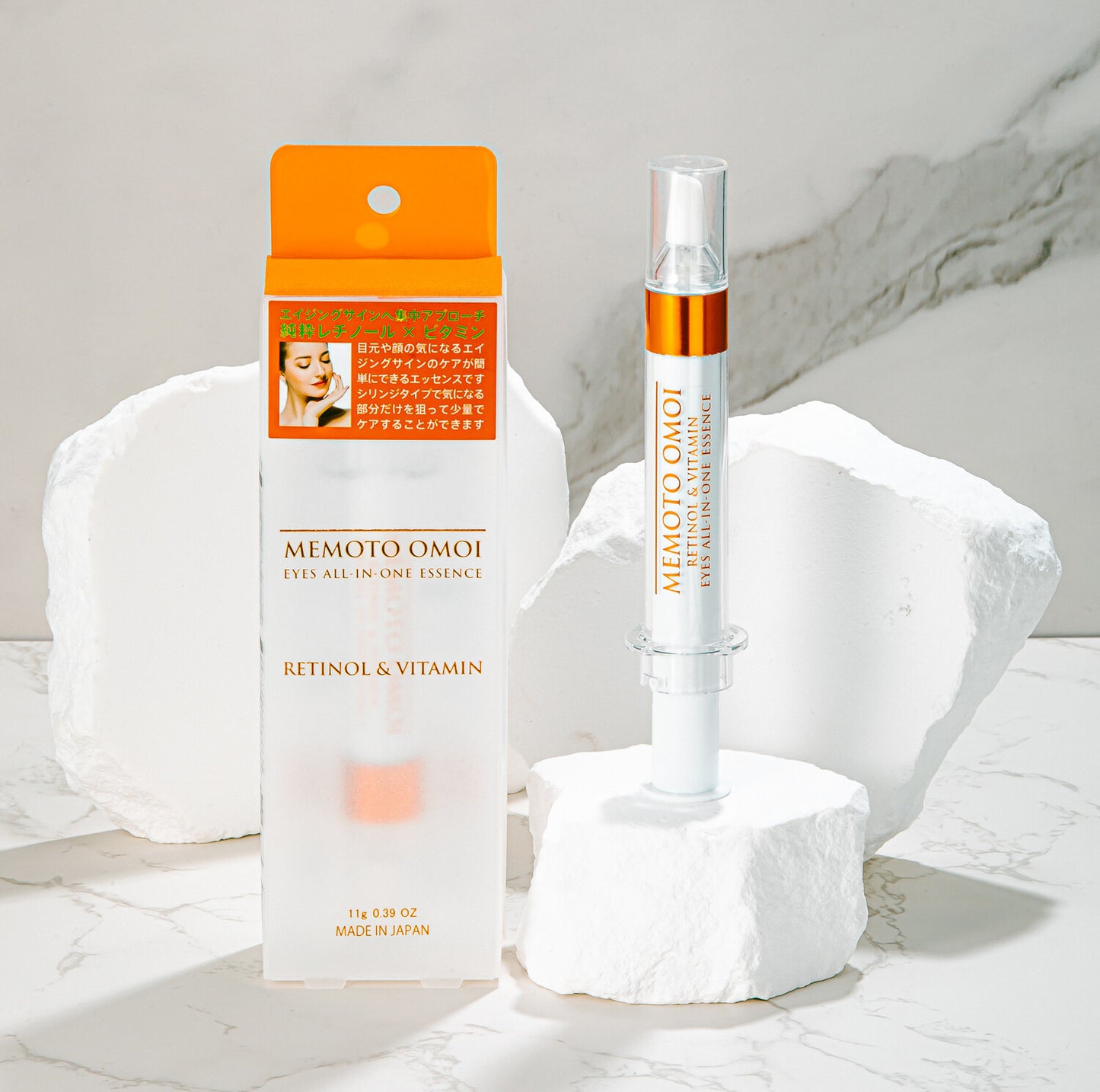 Two sleek, syringe-like containers of MEMOTO OMOI EYES ALL-IN-ONE ESSENCE RETINOL & VITAMIN stand upright against a reflective surface, illuminated by soft pink and orange hues. Elevate your skincare routine today by purchasing at MyAllures.