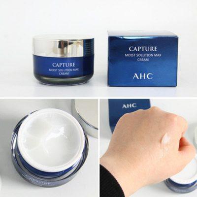 Image showing a blue jar of AHC Capture Solution Prime Moist Cream next to its box, with a white cream swatch on a hand in a close-up view. Buy at MyAllures for the best deals!