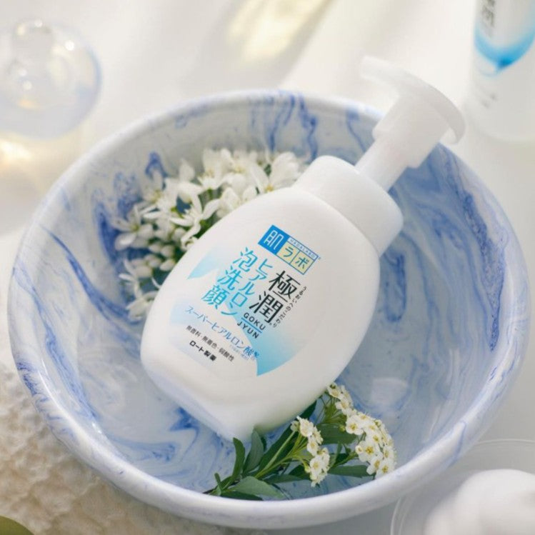 Image of a pump bottle labeled "HADALABO ROHTO GOKUJYN HYALURONIC ACID CLEANSING FOAM" with a pump of foam beside it. Background includes water bubbles and the text "Hydration Starts with Cleansing". Buy at MyAllures for the ultimate skincare experience.