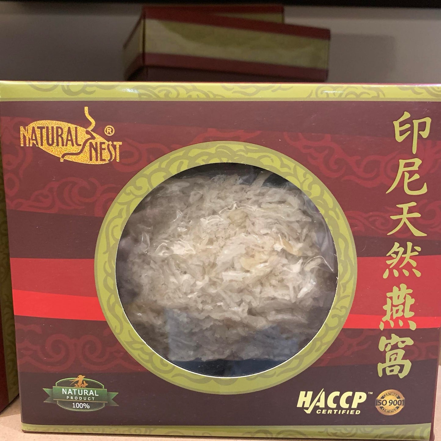 A box labeled "BIRDNEST PREMIUM WHITE SMALL BROKEN BIRD'S NEST," containing a vacuum-sealed package of dried edible bird's nests. The box features red and black stripes with gold Chinese characters on the top. Purchase this exquisite item at MyAllures.